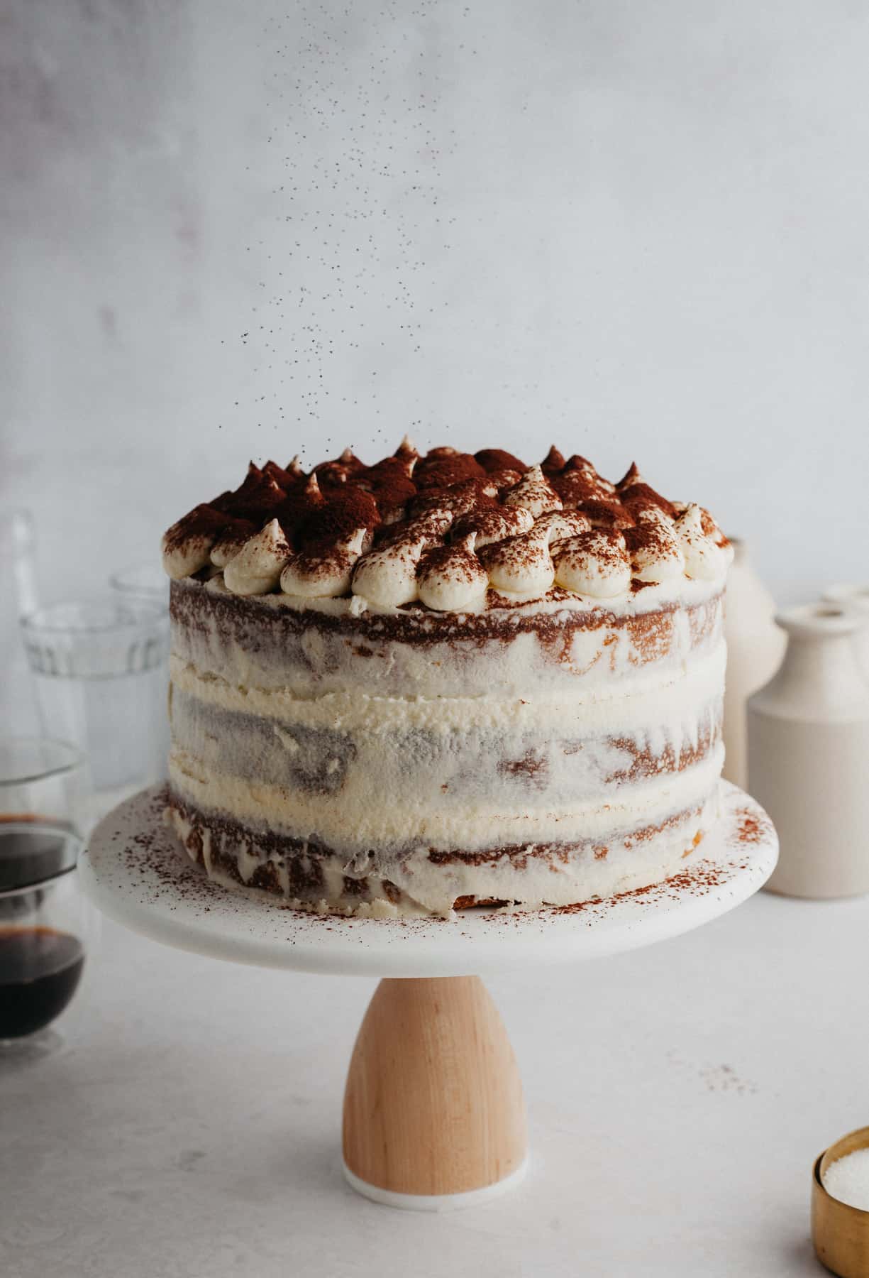 A tiramisu layer cake on a white cake stand