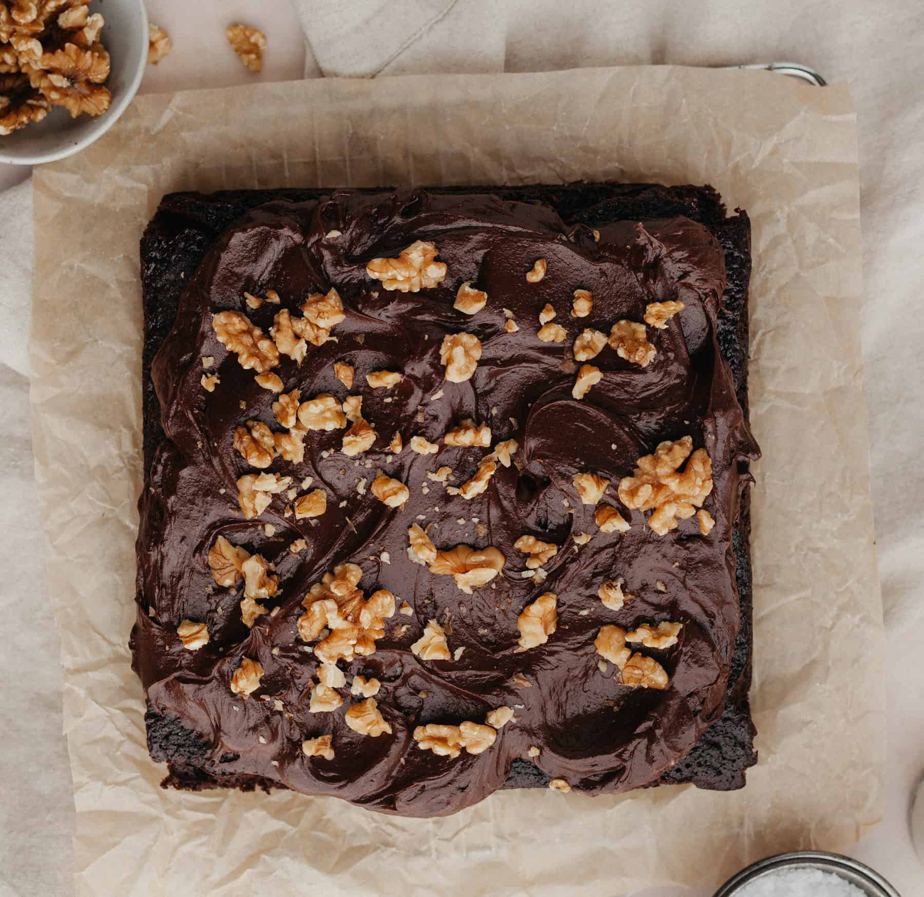 A square chocolate walnut cake on brown parchment paper