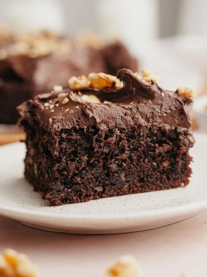 A slice of chocolate cake with chocolate frosting on a plate.