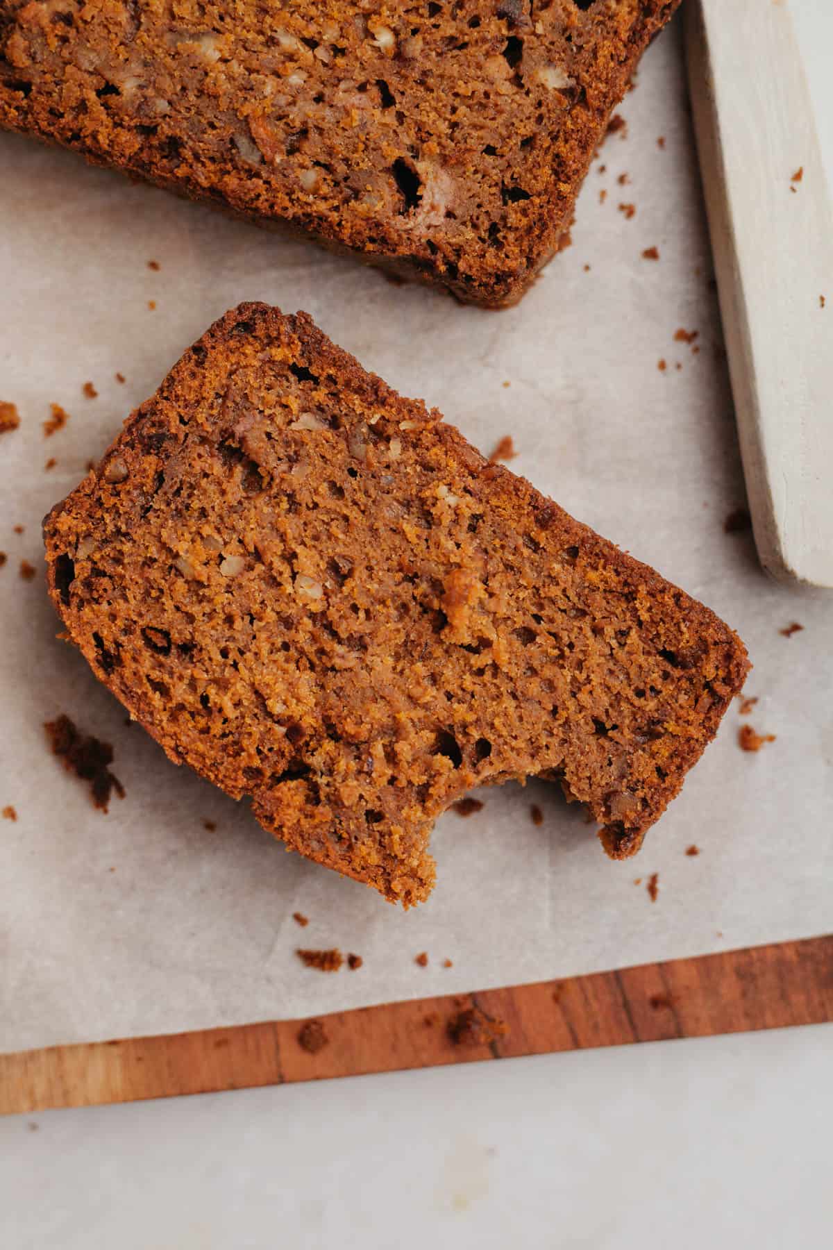 A slice of healthy pumpkin banana bread on parchment paper.