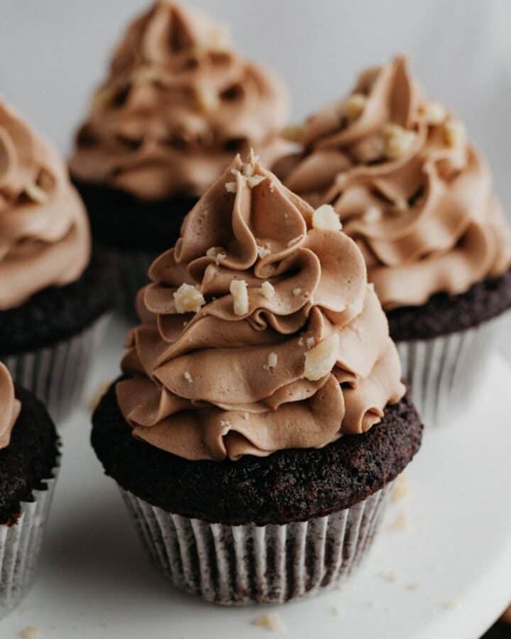chocolate frosted chocolate cupcakes, sprinkled with chopped hazelnuts.