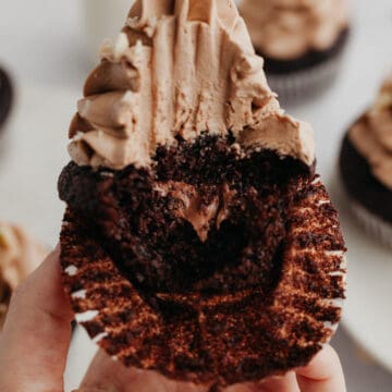 A chocolate frosted cupcake with a bite taken out, showing a nutella filling.