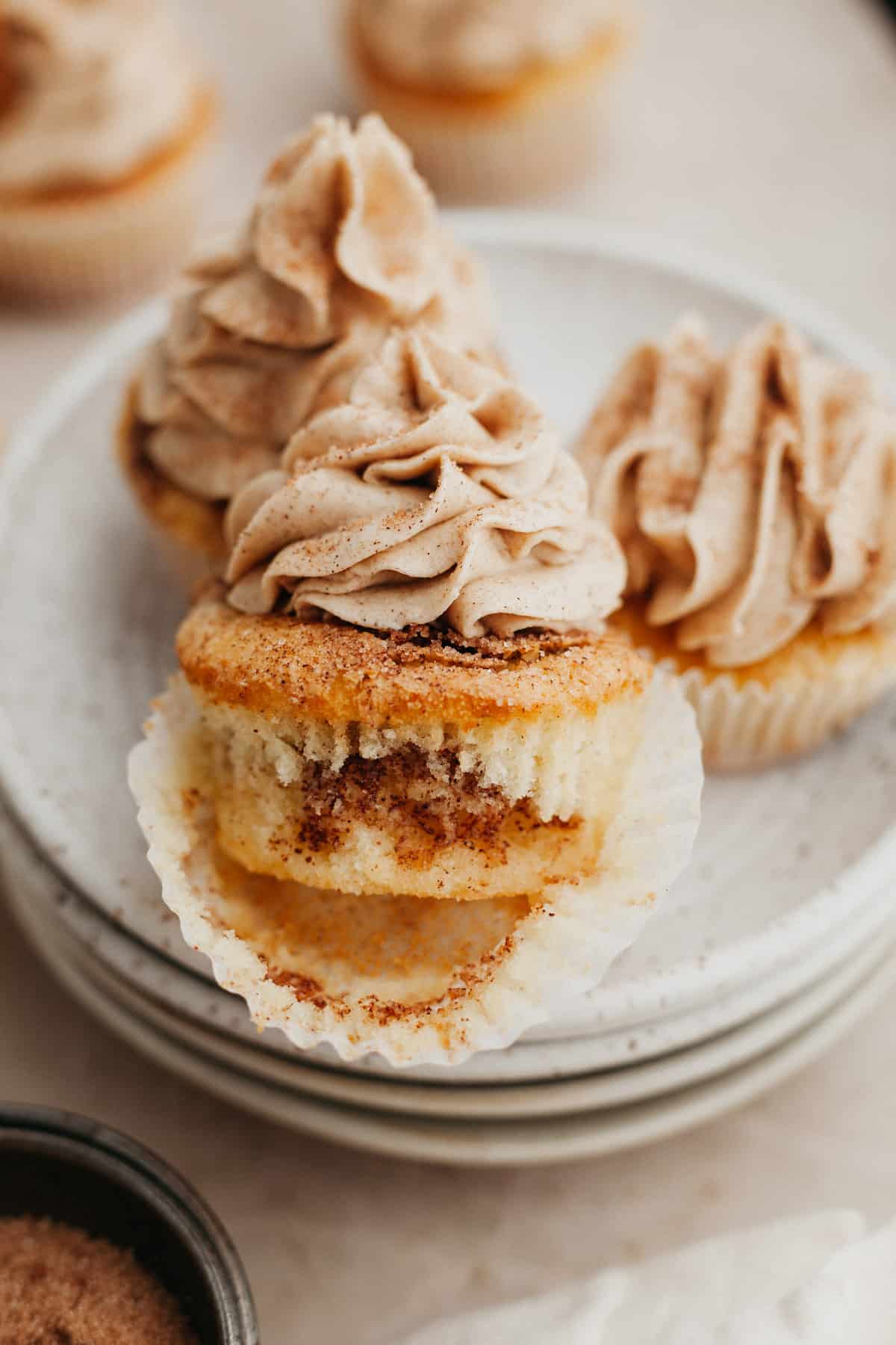 three cinnamon swirl cupcakes on a beige plate.