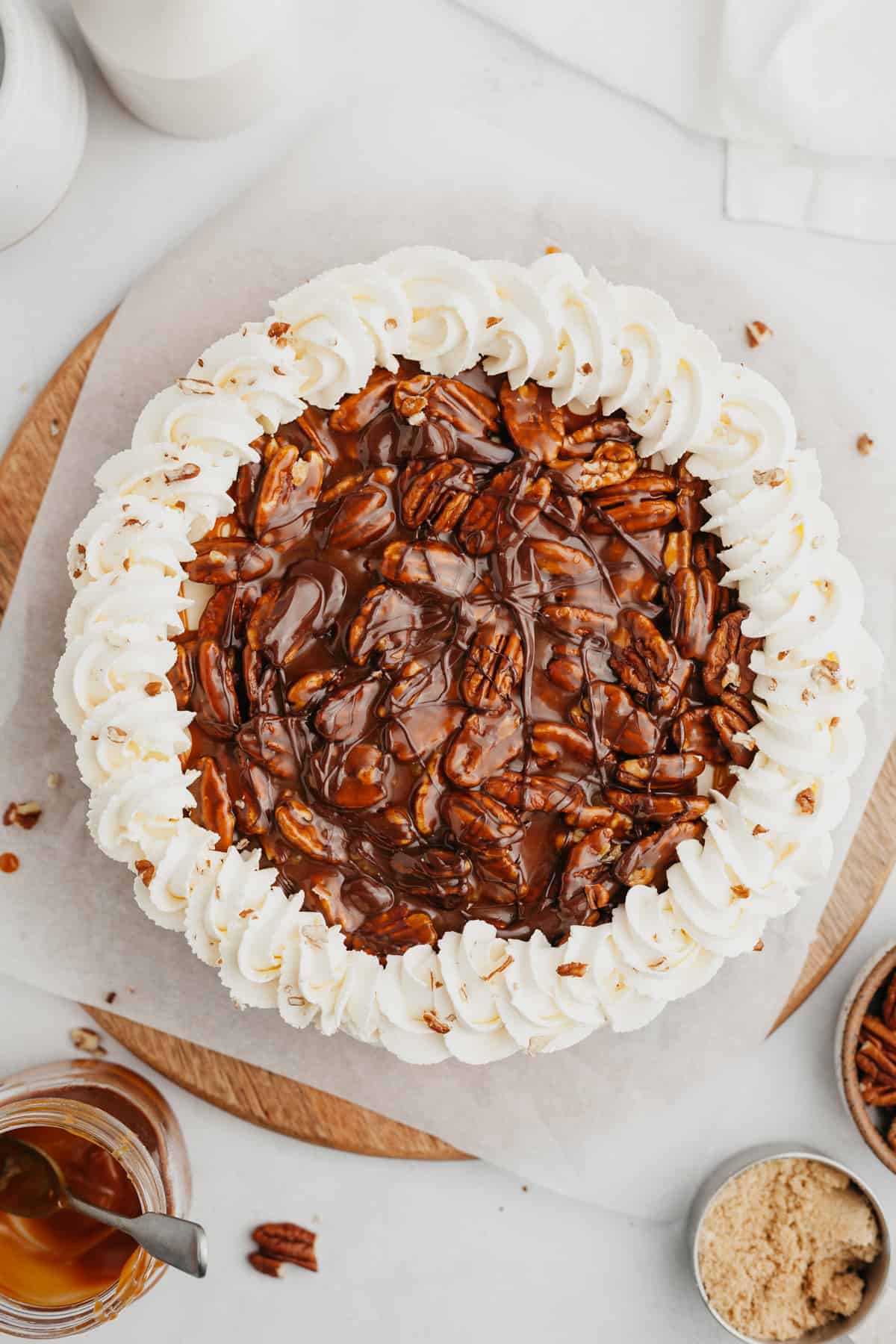 An overhead shot of a turtle pie covered in pecans and whipped cream.