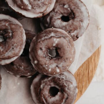 A pile of chocolate cake doughnuts on parchment paper.