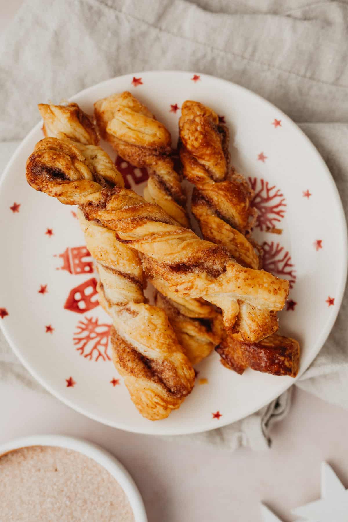 A small red and white plate with cinnamon sugar twists on it.