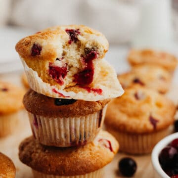 A stack of cranberry muffins on parchment paper.