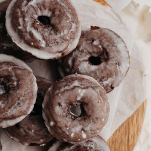 A pile of chocolate cake doughnuts on parchment paper.