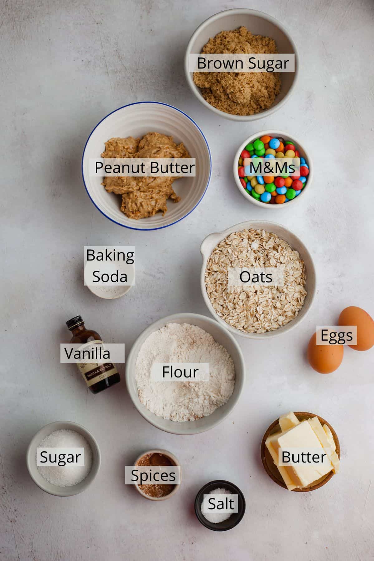 all the ingredients for oatmeal peanut butter m&m cookies weighed out in small bowls.