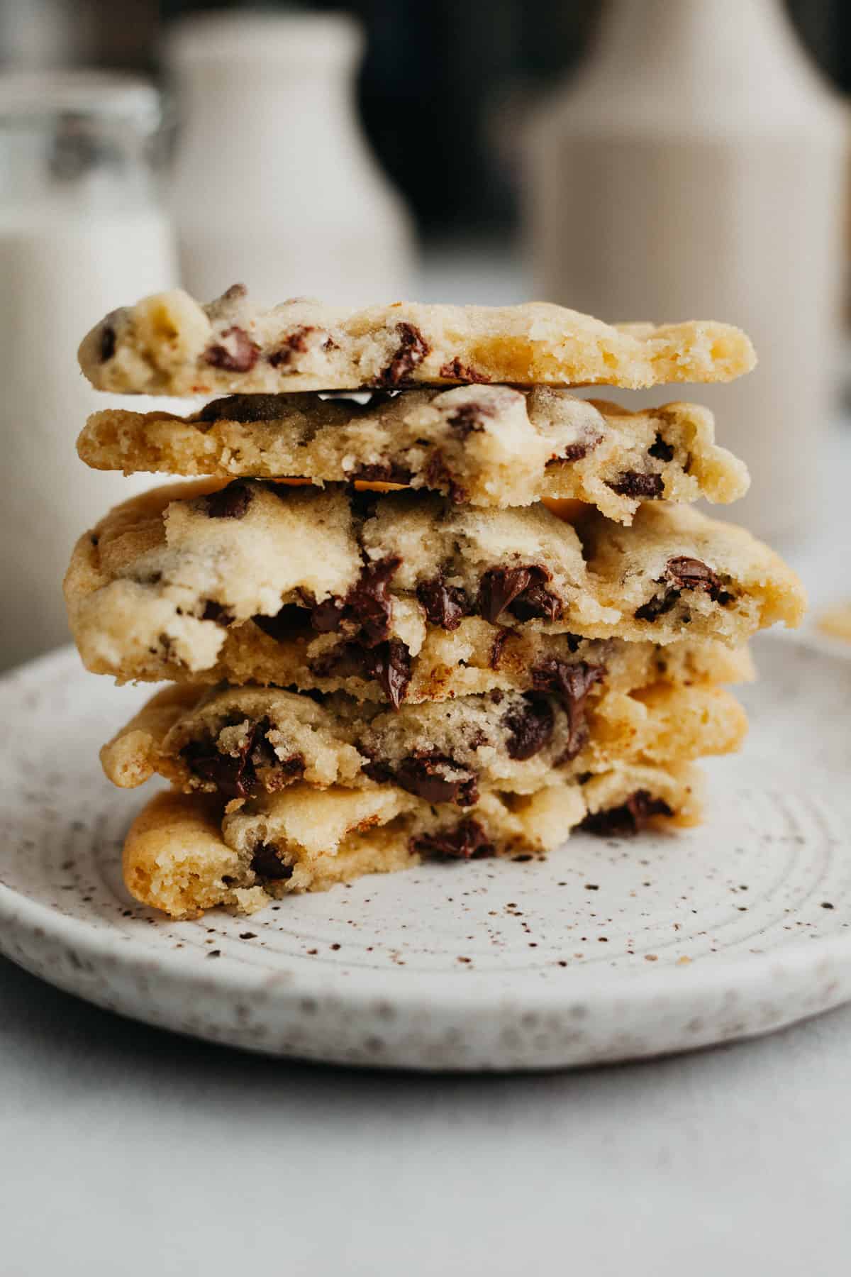 A stack of chocolate chip cookies broken in half on a small plate.