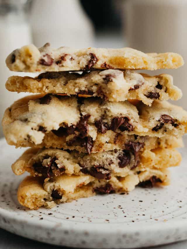 A stack of chocolate chip cookies broken in half on a small plate.