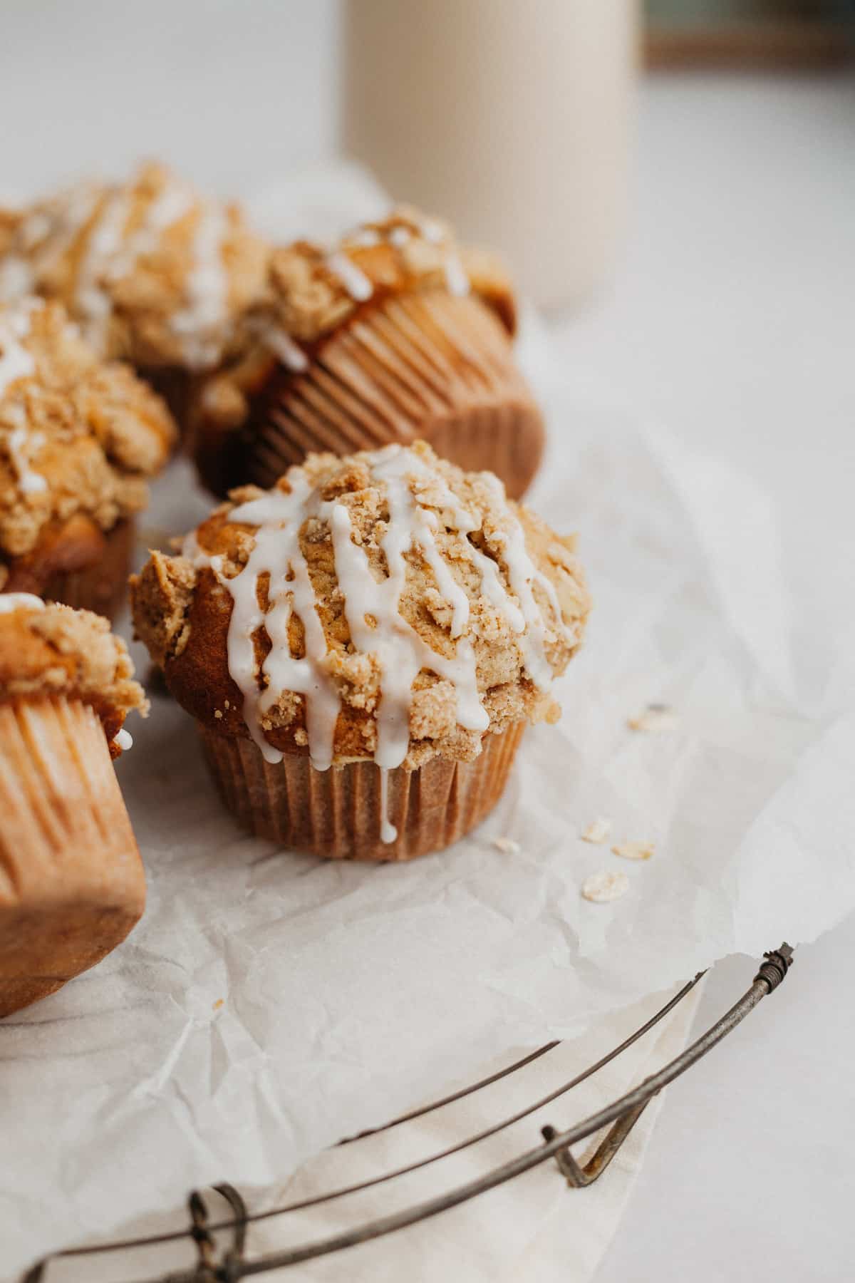 several muffins drizzled with a glaze on top of parchment paper.