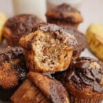 Banana muffins in a pile, one with a bite taken out of it.