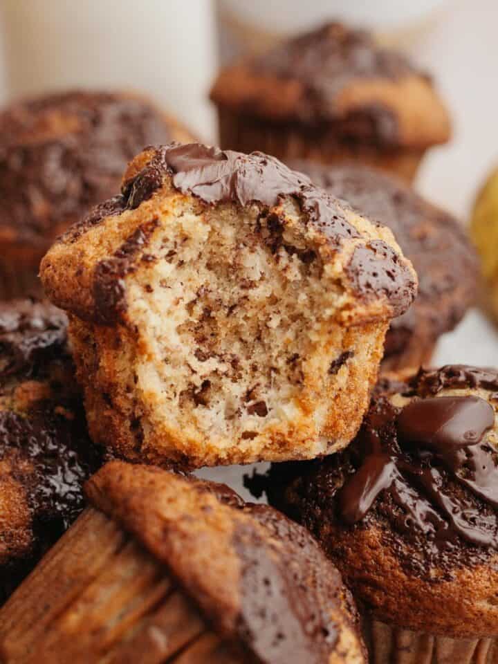 Banana muffins in a pile, one with a bite taken out of it.