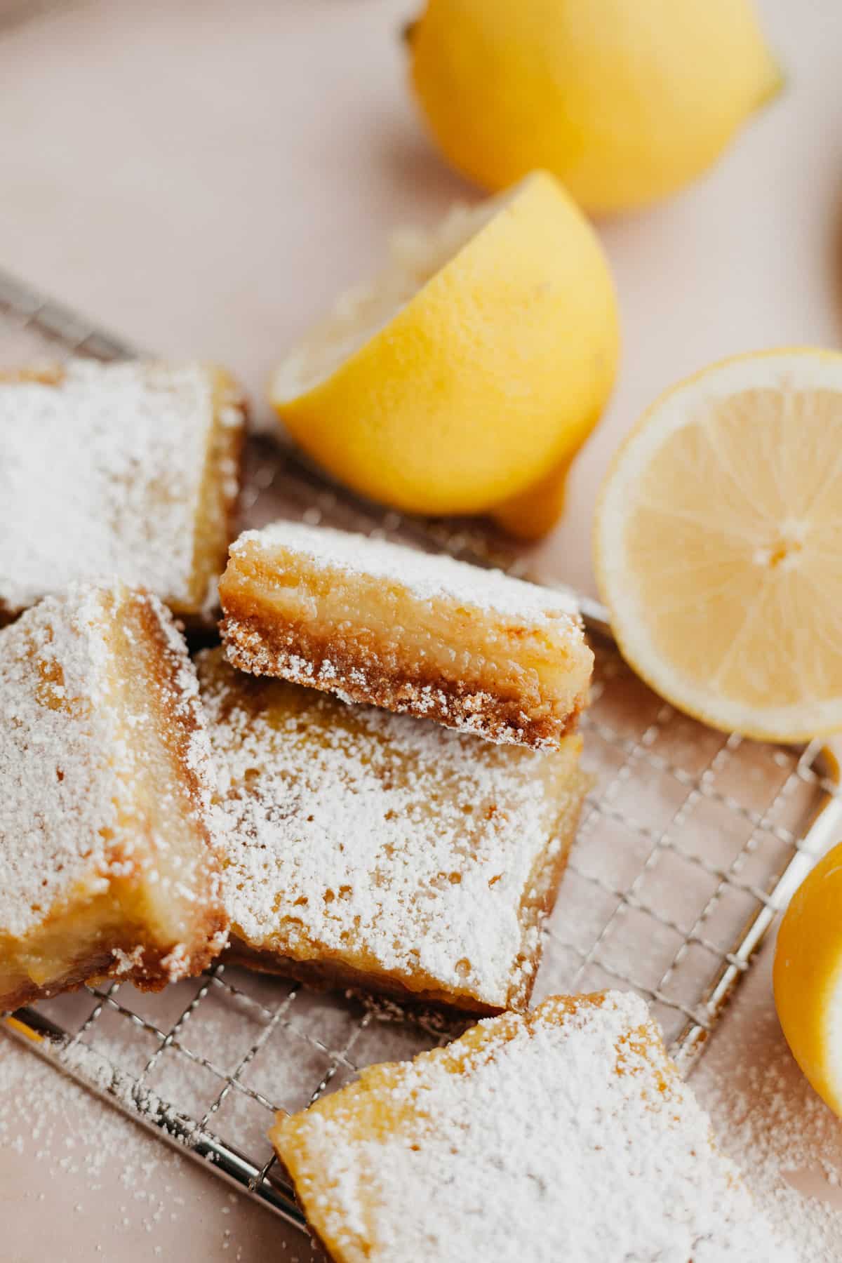 several lemon bars dusted with confectioners' sugar on a cooling rack.