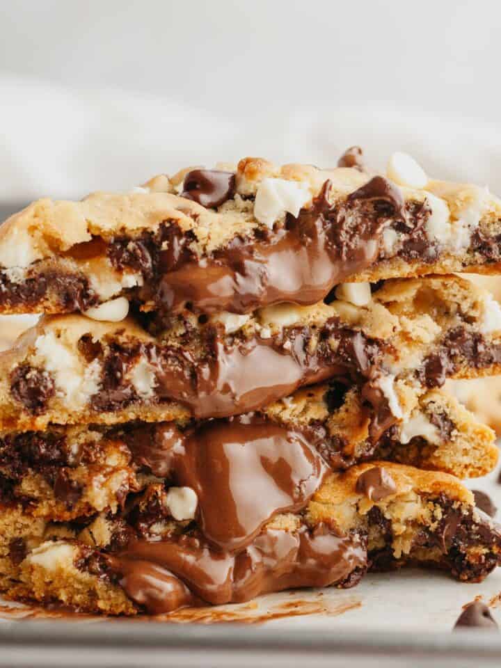 A stack of chocolate stuffed cookies, split in half to show the chocolate.