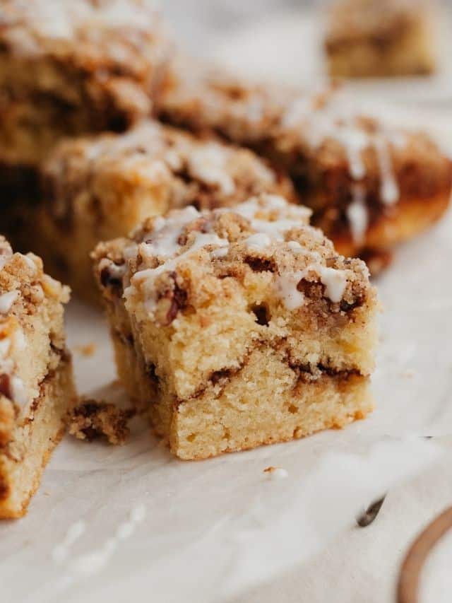 A close up of a slice of pecan sour cream coffee cake on parchment paper.