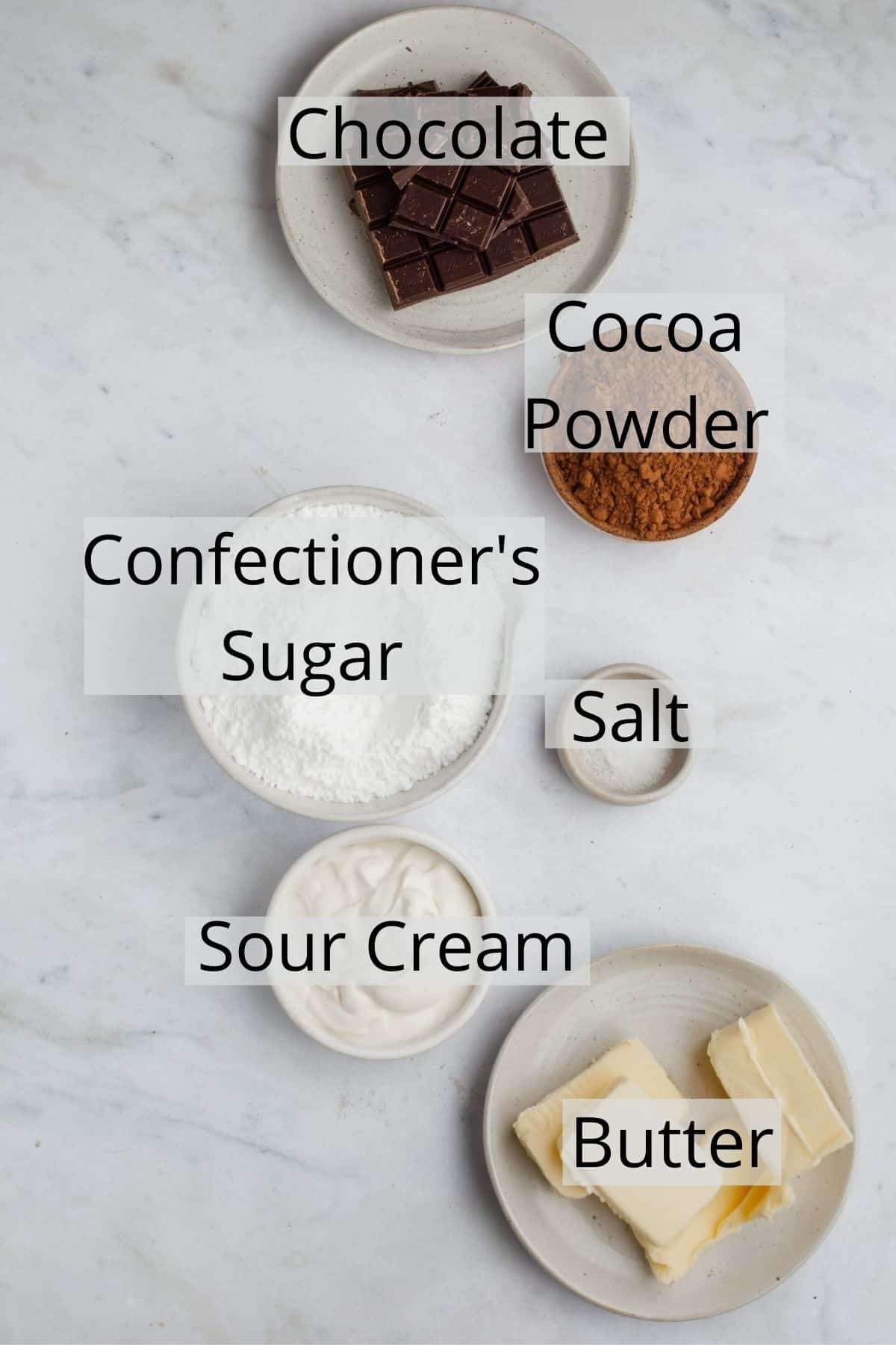 all the ingredients for chocolate sour cream frosting weighed out in small bowls.