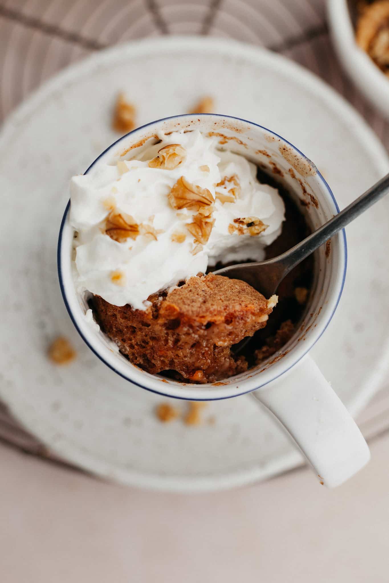 An overhead shot of a carrot mug cake topped with whipped cream.