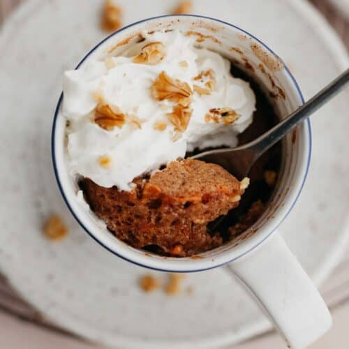An overhead shot of a carrot mug cake topped with whipped cream.