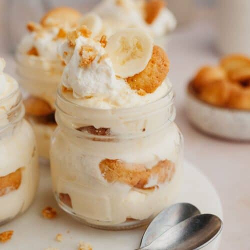 A close up of banana pudding in a jar on a marble surface.