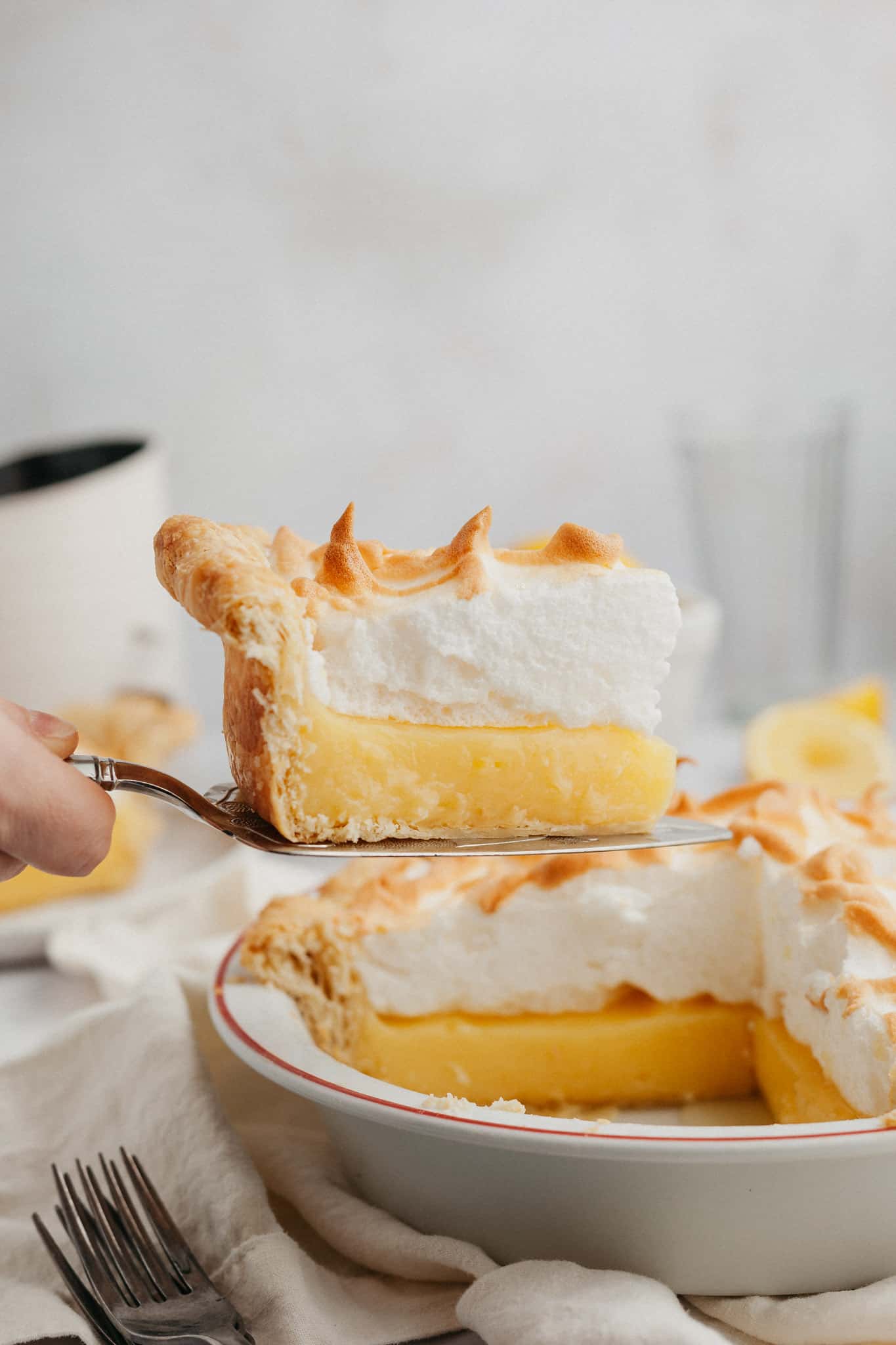 a slice of lemon meringue pie being lifted out with a serving knife.