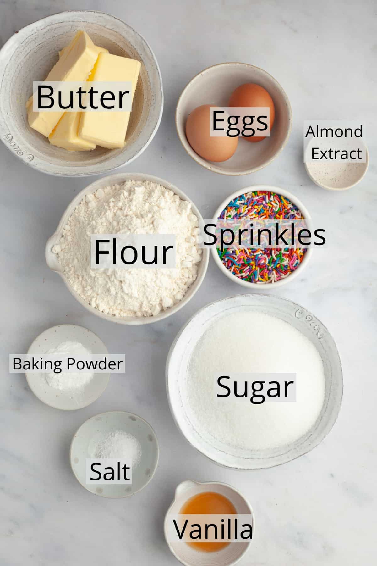 All the ingredients needed to make sugar sprinkle cookies weighed out into small bowls.