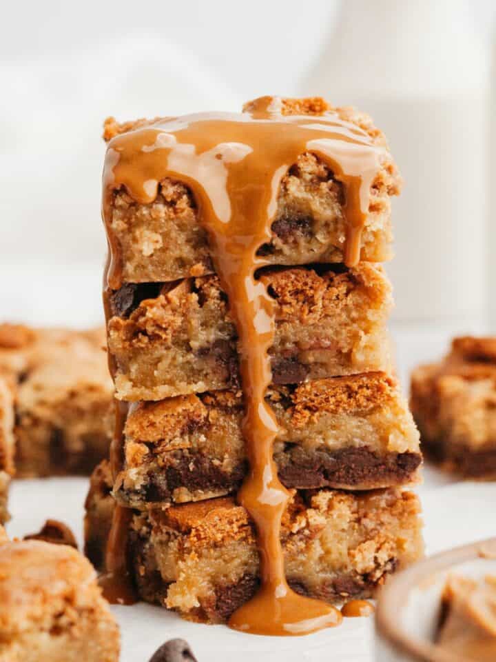 A stack of biscoff blondies with melting biscoff dripping down the stack.