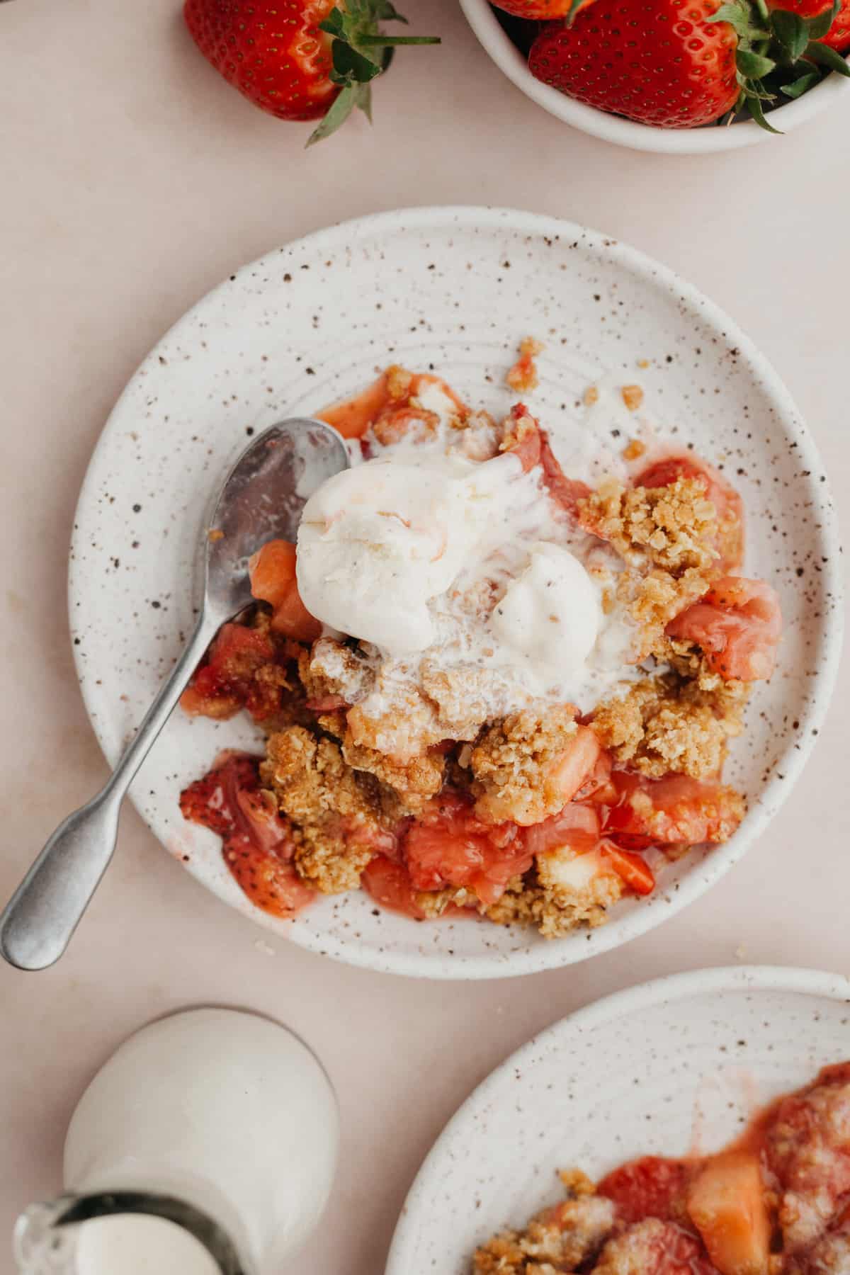 a small plate with strawberry crisp on it and a scoop of vanilla ice cream.