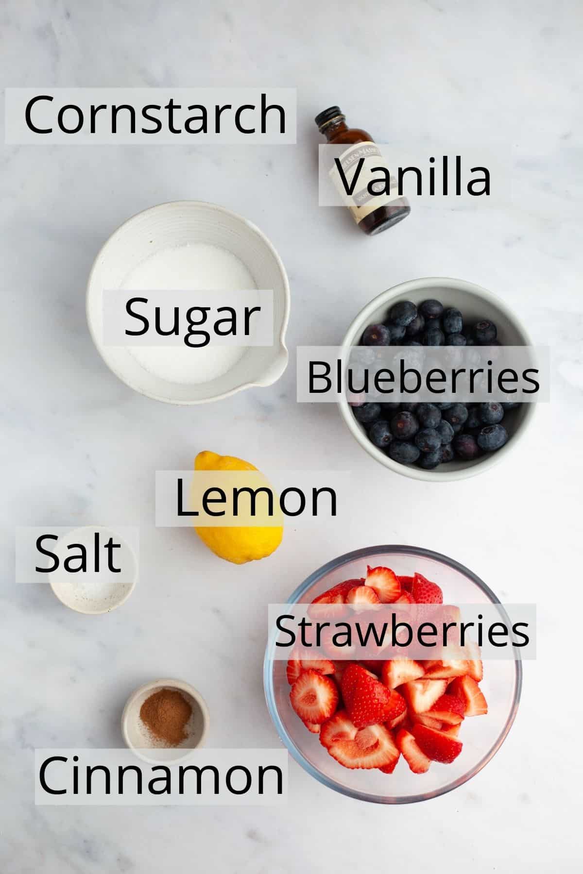 All the ingredients needed for a strawberry blueberry pie filling weighed out into small bowls.