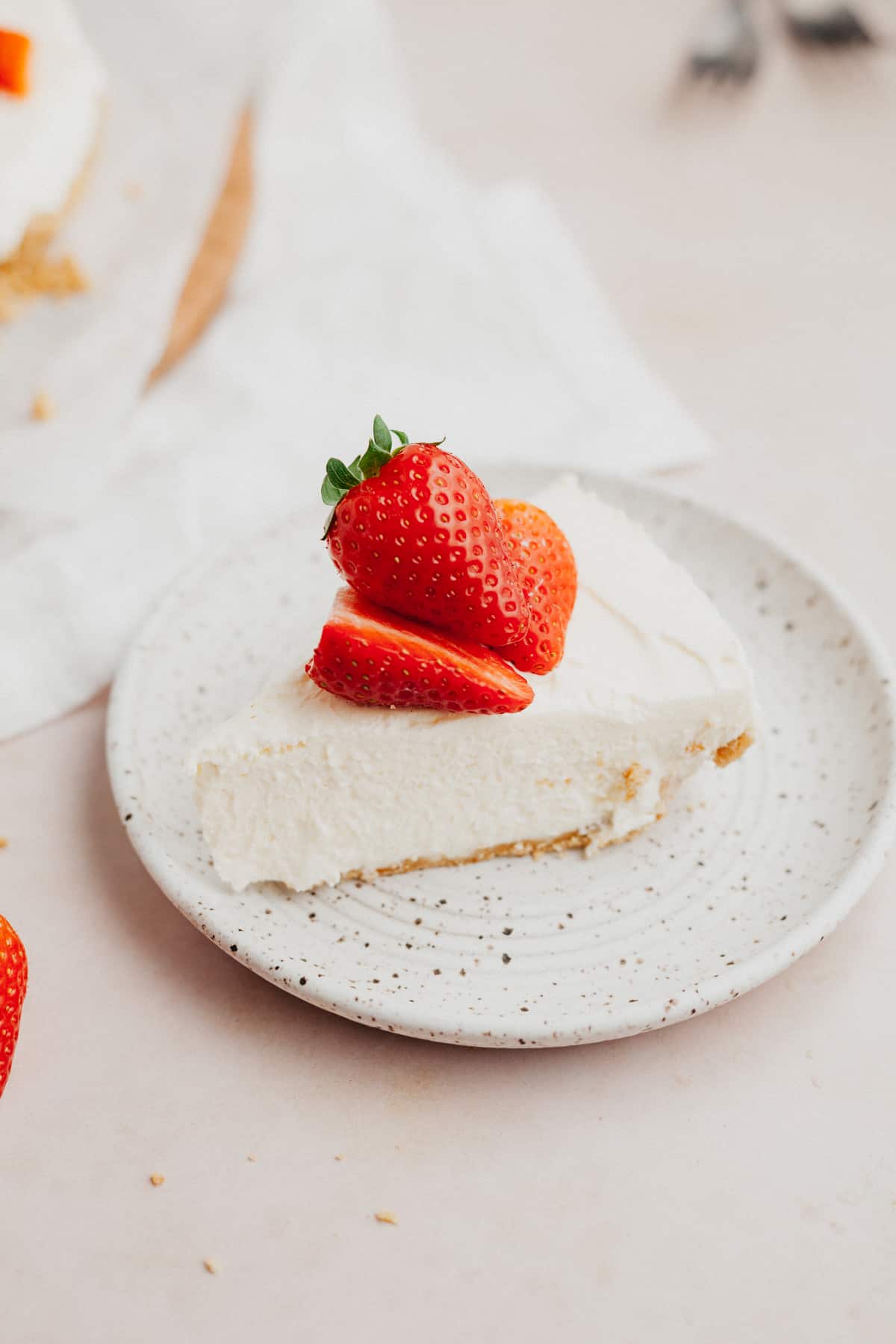 A slice of mascarpone cheesecake topped with sliced strawberries on a small plate.