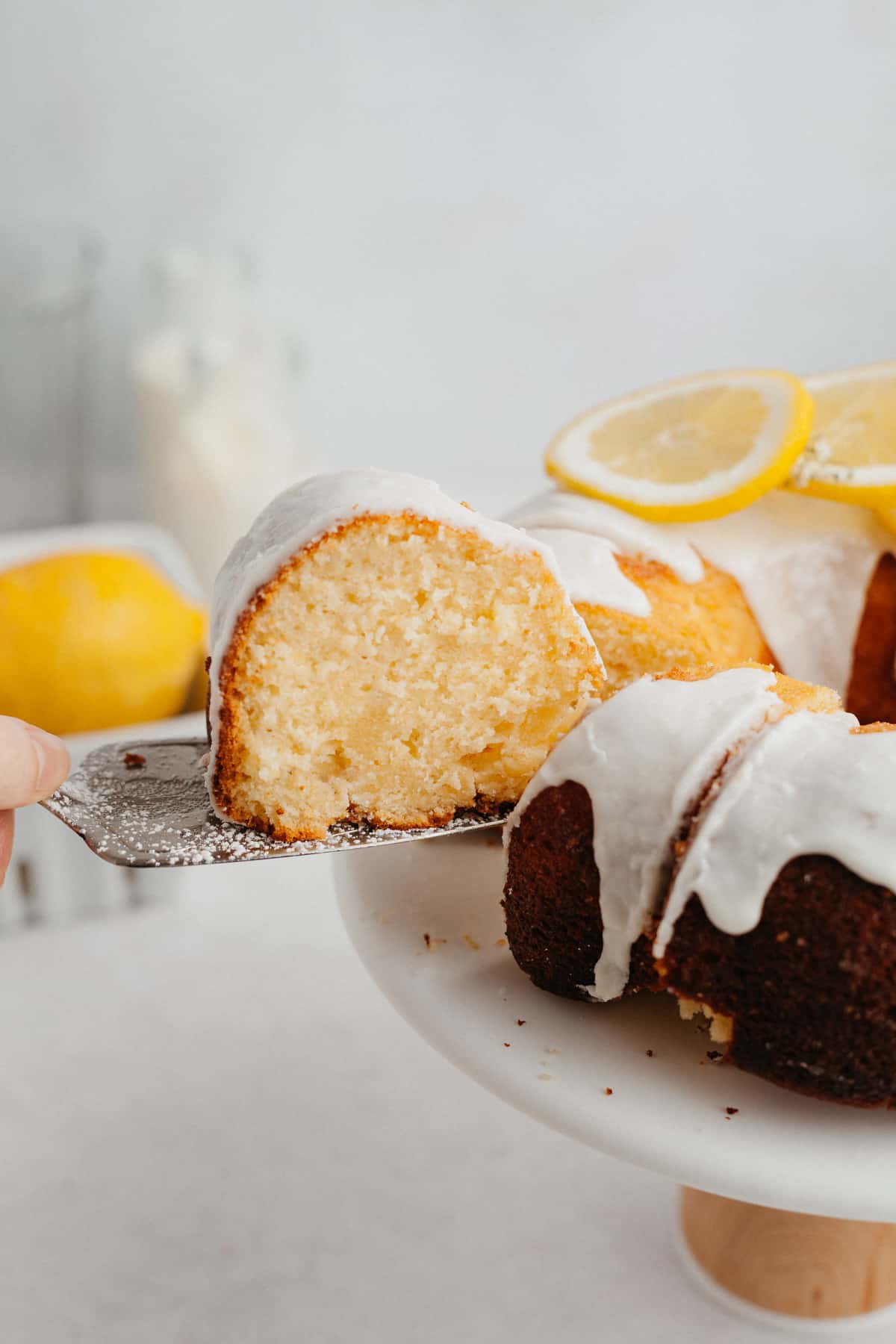 A slice of lemon bundt cake being lifted out with a silver cake server.