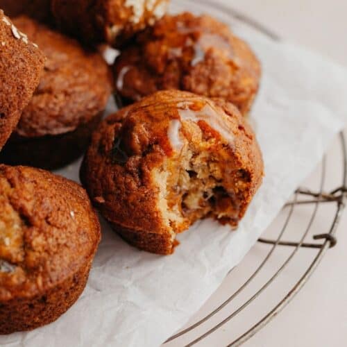 Several muffins on parchment paper, one muffin has a bite taken out of it.