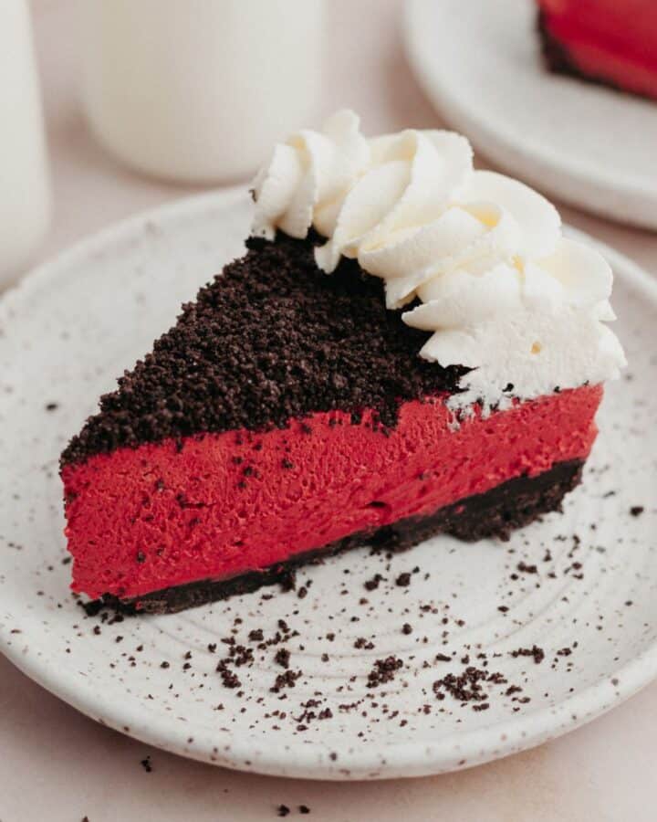 A slice of red velvet oreo cheesecake on a small white plate.