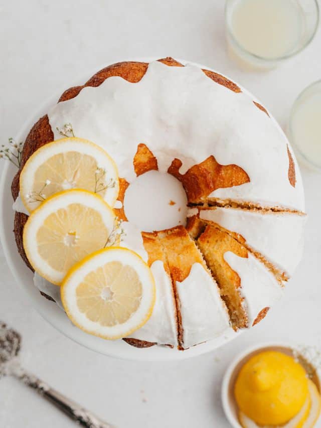 An overhead shot of a lemon bundt cake with a white glaze and three slices of lemon on top.