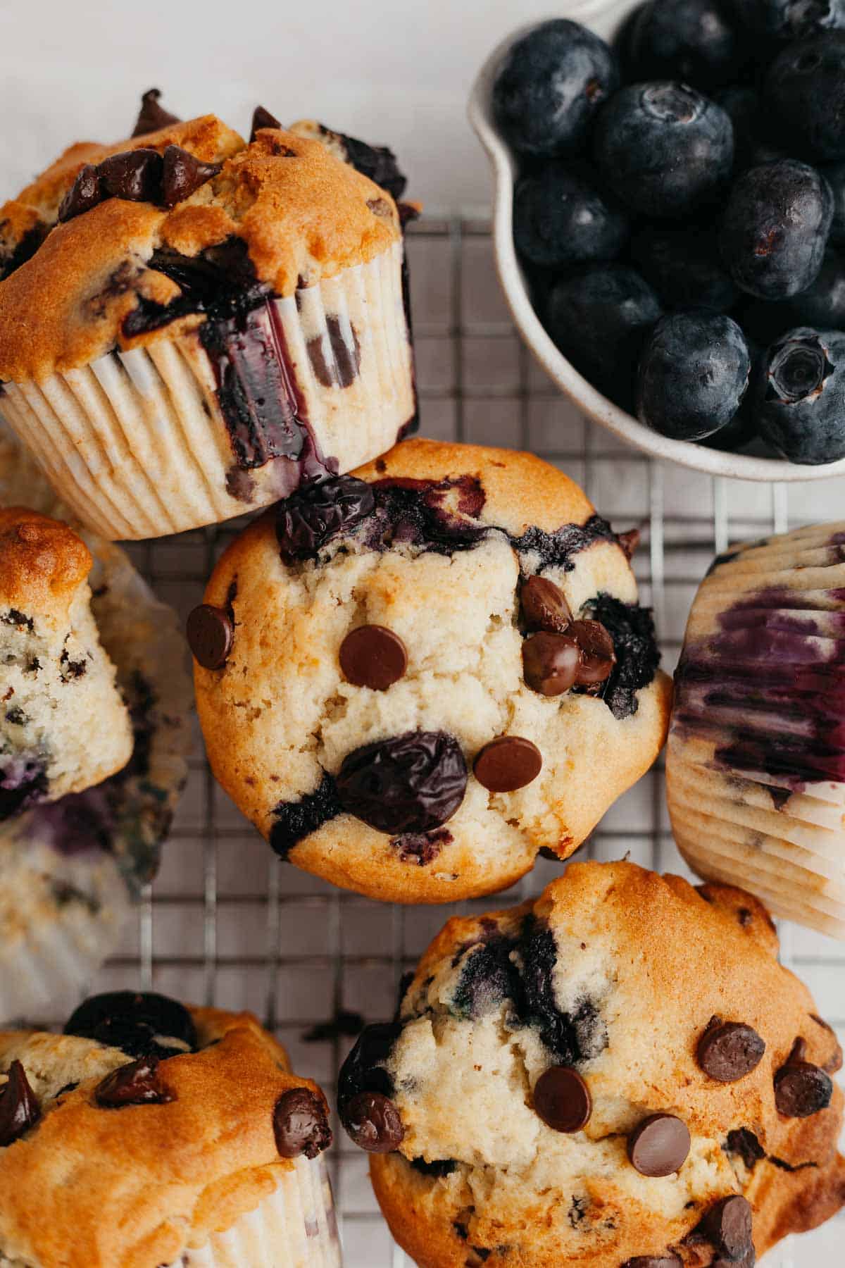 Several blueberry chocolate chip muffins on a wire cooling rack.