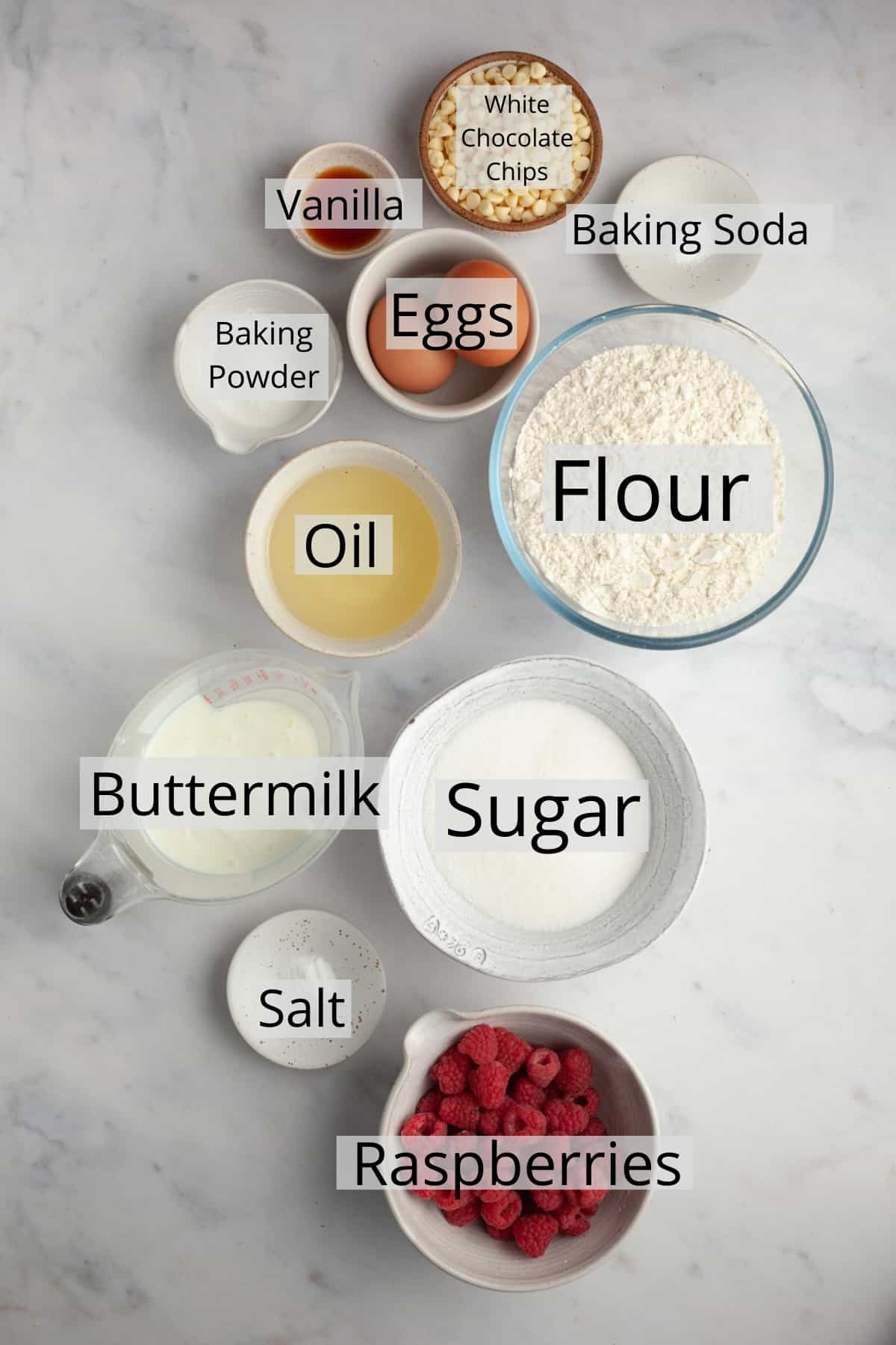 all the ingredients needed to make raspberry white chocolate muffins in small bowls.