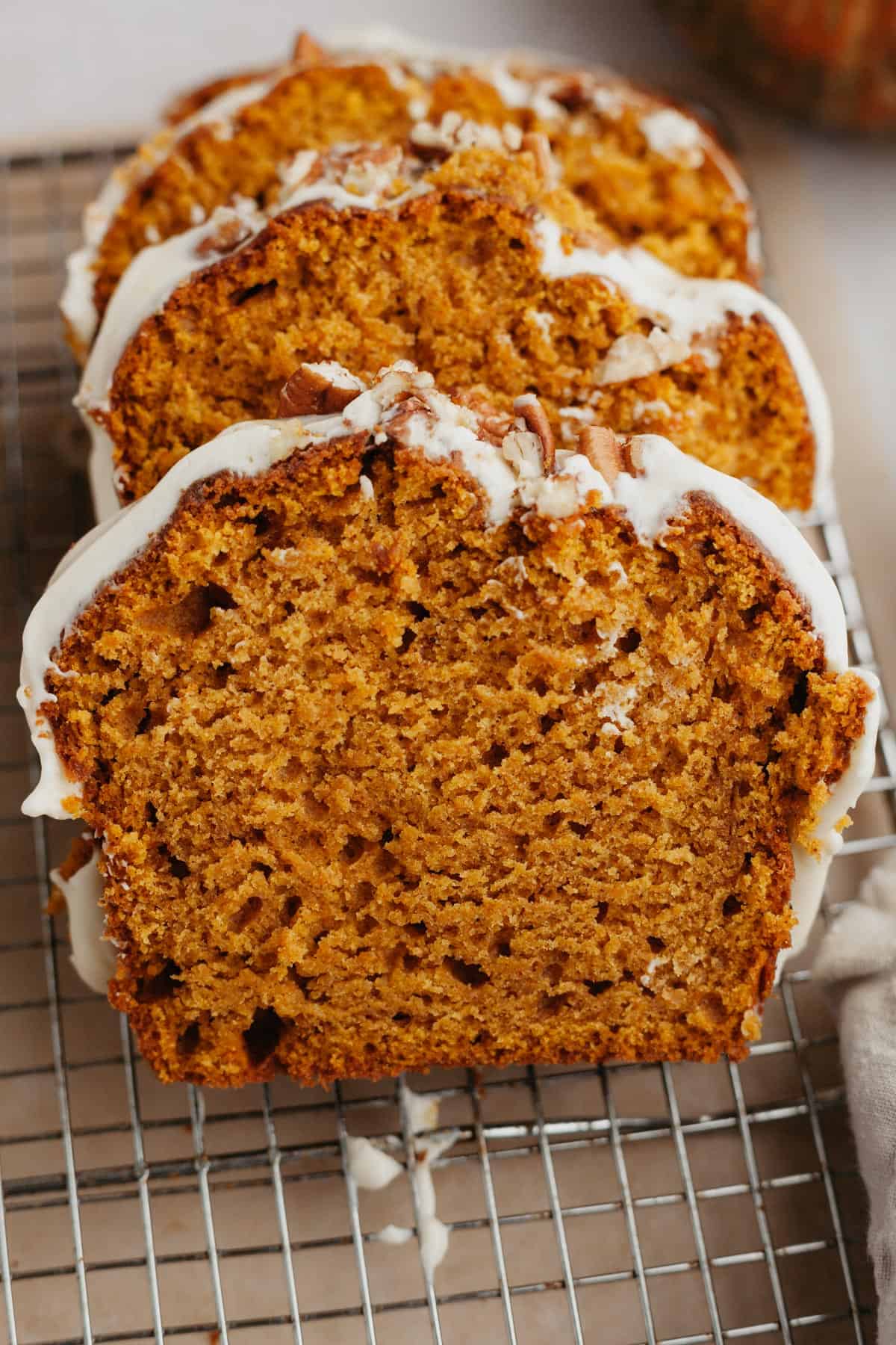 Three slices of pumpkin bread on a wire cooling rack.