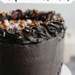 A close up of a frosted black velvet cake with orange and white sprinkles.