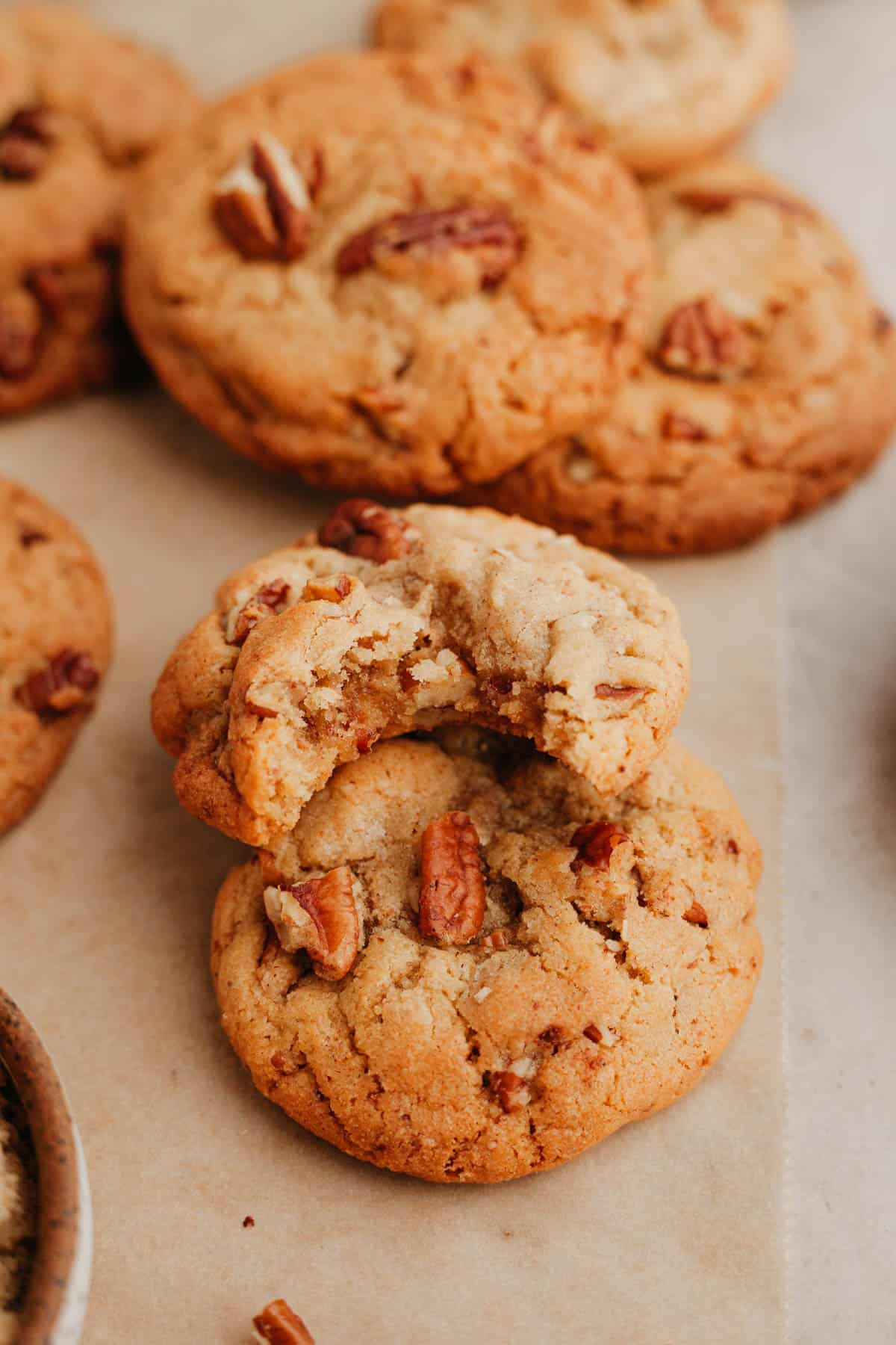 Two pecan cookies on top of each other, one has a bite taken out of it.