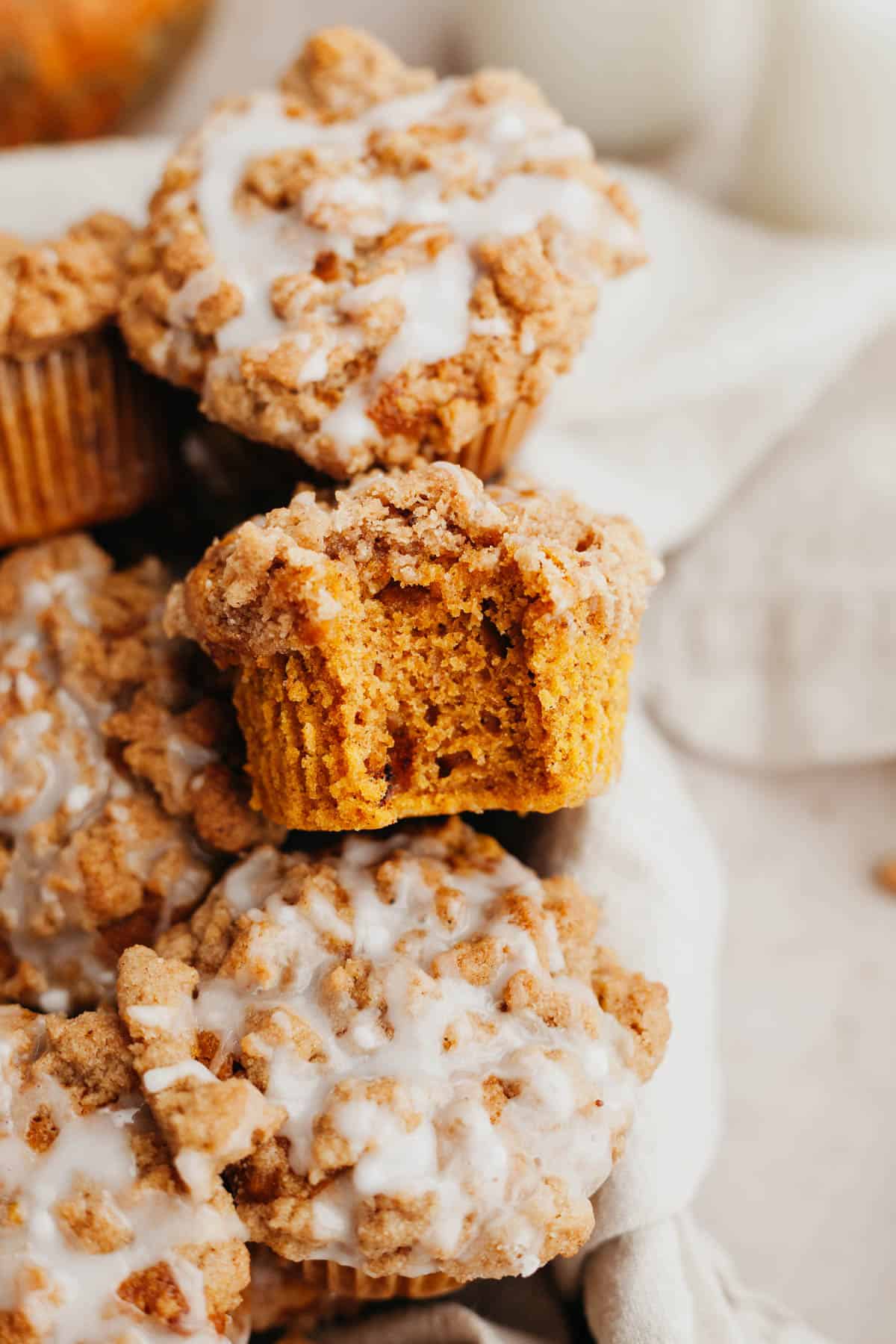 A close up of a pumpkin muffin with a streusel topping, a bite has been taken out of it.