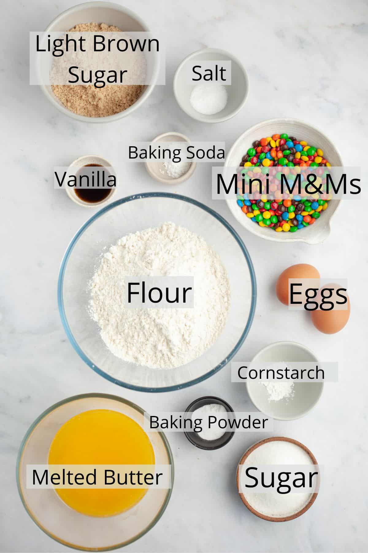 All the ingredients needed to make mini m&m cookies weighed out into small bowls.