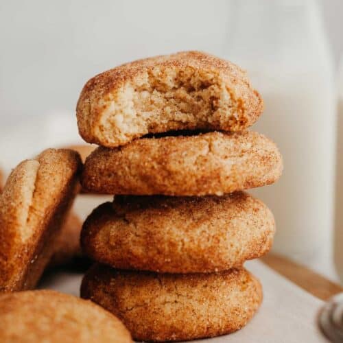 A stack of four snickerdoodle cookies, the cookie on the top has a bite taken out of it.