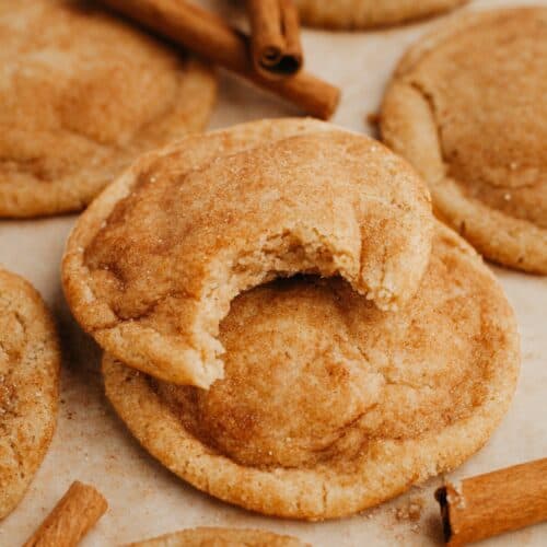 A close up of snickerdoodles, one has a bite taken out of it.