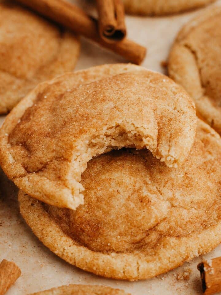 A close up of snickerdoodles, one has a bite taken out of it.