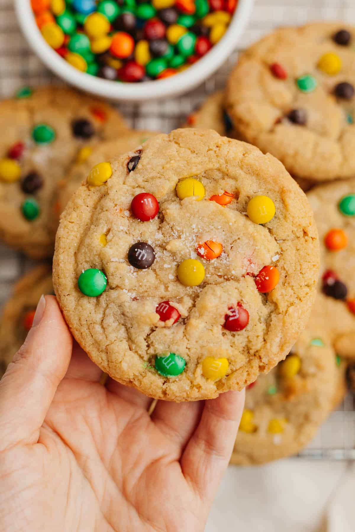 A hand holding a mini m&m cookie.