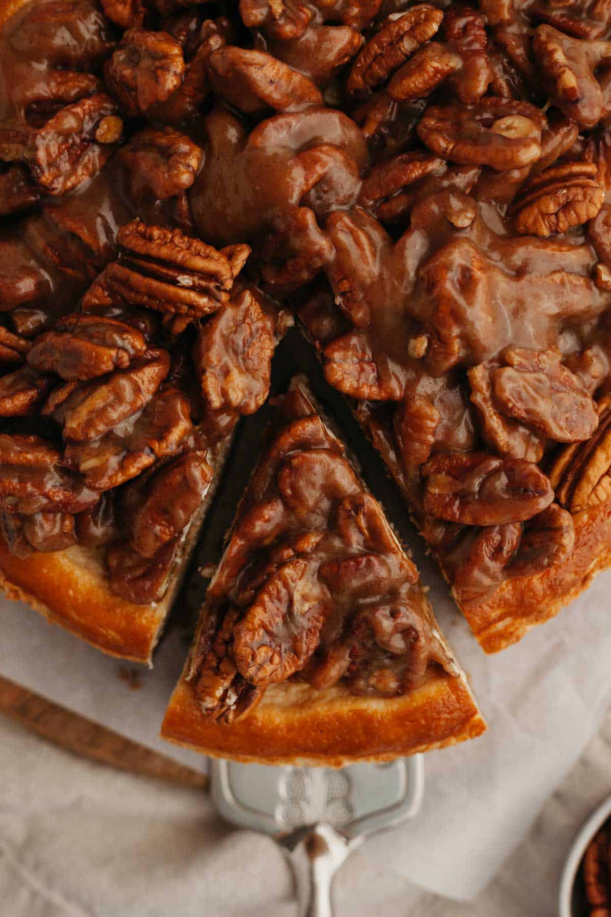 An overhead shot of a pecan pie cheesecake, one slice has been cut.