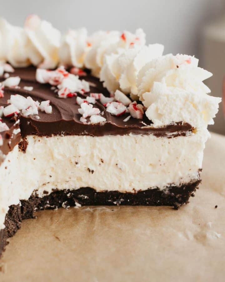 A close up of a peppermint bark cheesecake which has been cut, showing the inside of the cheesecake.