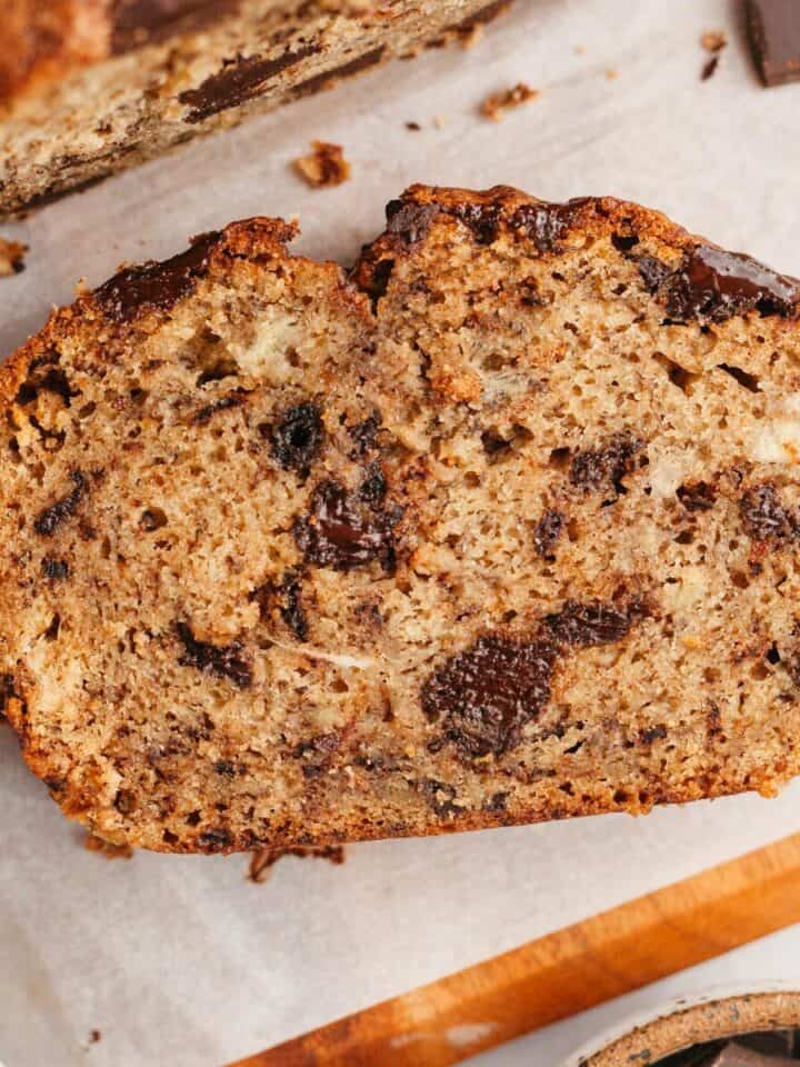 A slice of chocolate chunk banana bread on parchment paper.