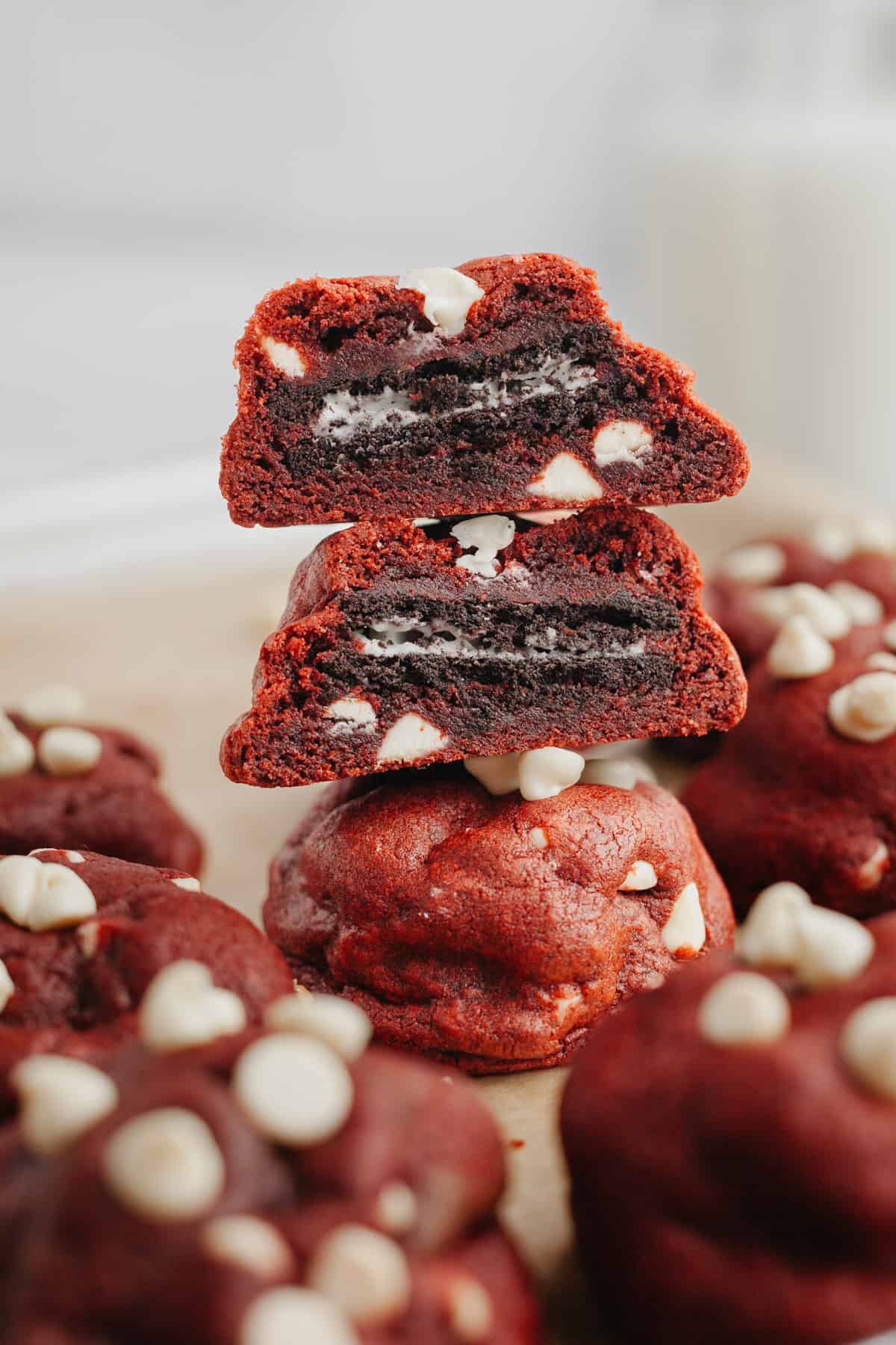 A stack of three red velvet cookies, they are cut in half showing they are stuffed with an Oreo.